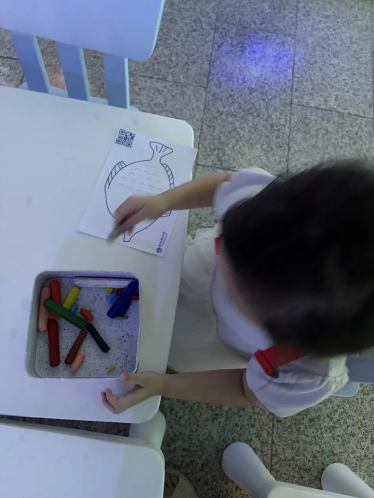 小孩用蠟筆彩繪海洋生物線稿